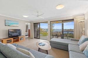 a living room with a couch and a tv at Riverdance Apartments in Mooloolaba