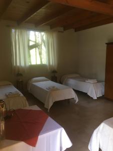 a room with three beds and a window at Posada Tanti El Durazno in Tanti