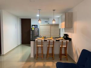 a kitchen with two bar stools and a refrigerator at Precioso apartamento con piscina. in San Gil
