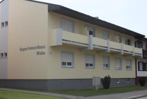 ein weißes Gebäude mit den Worten Wohnungsorganisationen wald in der Unterkunft Appartementhaus Waba in Podersdorf am See