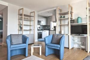 un salon avec deux chaises bleues et une télévision dans l'établissement Résidence Quai Sud- Le Charcot, à Saint-Malo