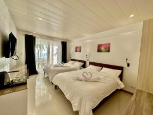 a bedroom with two beds with white sheets at Calypso Beach and Dive Resort in Boracay