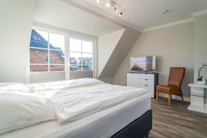 - une chambre blanche avec un lit et une chaise dans l'établissement Haus Strandoase, à Westerland