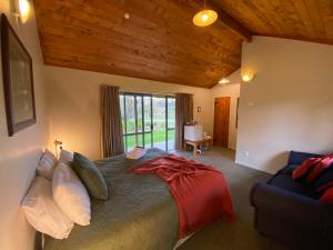 Makoura Lodge في Apiti: غرفة نوم بسرير واريكة ونافذة
