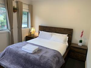 - une chambre dotée d'un grand lit avec des draps et des oreillers blancs dans l'établissement Olinda Village Apartment - A2, à Olinda