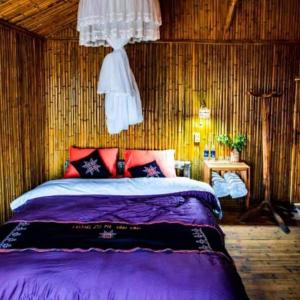 a bedroom with a bed with purple sheets and red pillows at Bình Minh Homestay in Nam Giang