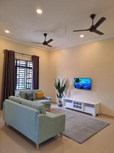 sala de estar con 2 sofás y TV en la pared en ZN Homestay Gong Badak en Kampong Pengkalan Maras