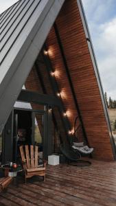 a house with a wooden deck with chairs on it at Nordik Cabin - Aframe with 2 bedrooms in Mărişel