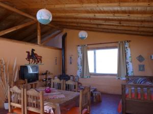 comedor con mesa, TV y ventana en Valle del Cielo en Uspallata