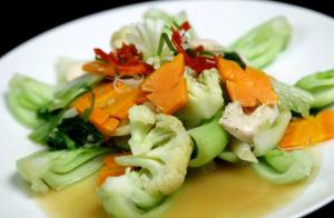 a white plate of food with vegetables on it at Laxston Hotel in Yogyakarta