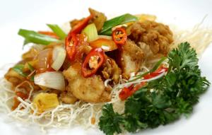 a plate of food with chicken and vegetables on noodles at Laxston Hotel in Yogyakarta