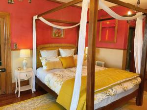 a bedroom with a canopy bed in a red wall at Tracy's Boutique B&B Farmstay in Wellsford