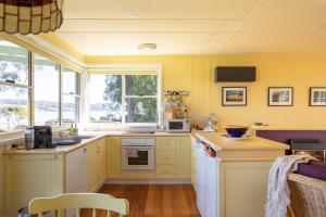 cocina con paredes amarillas y nevera blanca en Olive's Cottage, en Windermere