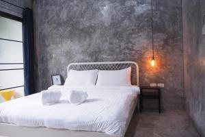 een slaapkamer met een bed met witte lakens en kussens bij Baan Trok Bedroom Studio Maikhao in Mai Khao Beach