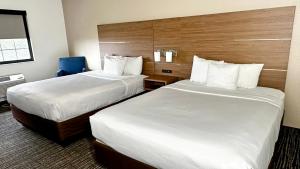 una habitación de hotel con 2 camas y una silla azul en Estherville Hotel & Suites, en Estherville
