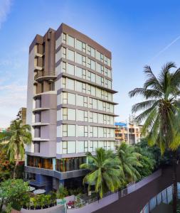 a tall building with palm trees in front of it at Lemon Tree Hotel, Kalina, Mumbai in Mumbai