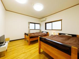 a bedroom with two beds and a desk and a tv at Ureshino Onsen Kotobukiya in Ureshino