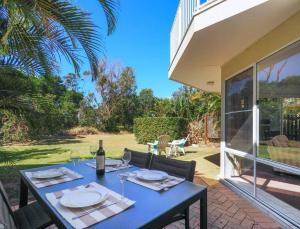 a blue table with a bottle of wine on a patio at Beachfront Retreat - Ducted Air - Free Wifi in Coffs Harbour