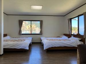 two beds in a room with two windows at Sea Tiger Island Inn Shodoshima in Shodoshima