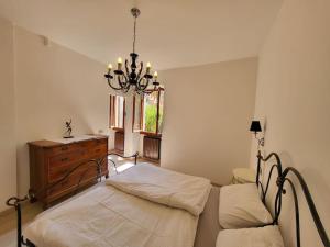 una camera con letto, cassettiera e lampadario a braccio di Villa Olivo a Limone sul Garda