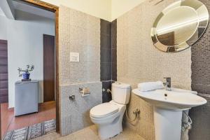 a bathroom with a toilet and a sink and a mirror at StayVista at Stonehill Manor with Outdoor Sitting in Dharamshala