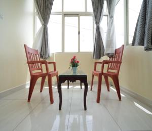 two chairs and a table with a vase of flowers at Nadanam Inn in Puducherry