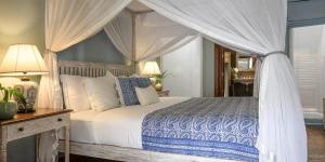 1 dormitorio con cama con dosel, mesa y lámparas en Maniumpathy Hotel en Colombo