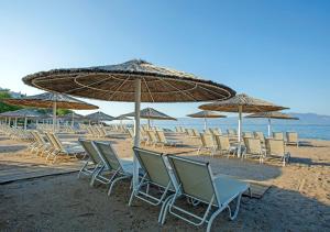 a row of chairs and umbrellas on a beach at CHARM BEACH HOTEL in Akyarlar