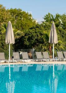 a group of chairs and umbrellas next to a swimming pool at CHARM BEACH HOTEL in Akyarlar
