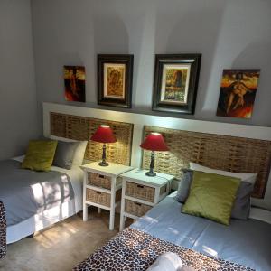 a bedroom with two beds and two lamps and pictures on the wall at Tucked-Away 1,2,3,bedroom houses in Nelspruit