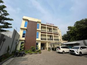 un hotel con dos coches estacionados frente a él en The Home Srengseng, en Yakarta