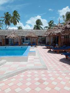 un complexe avec une piscine dotée de tables et de parasols en paille dans l'établissement Amani Hotel Paje, à Paje