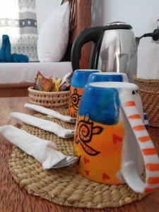 a table with two coffee mugs and a tea kettle at Amani Hotel Paje in Paje