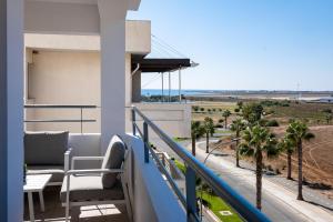 a balcony with a view of the ocean and palm trees at The Saline Views Makenzy in Larnaca