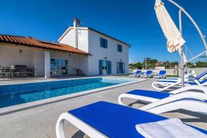 a villa with a swimming pool and lounge chairs at Villa Klara in Juršići