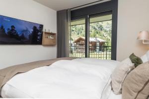 ein Schlafzimmer mit einem großen weißen Bett und einem großen Fenster in der Unterkunft Apartment in Chalet Pizzo Fiamma in Zermatt