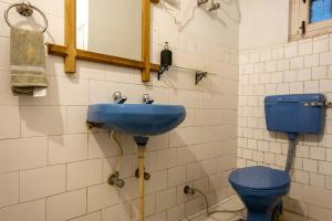 a bathroom with a blue sink and a toilet at Misty Mountains Cottage - In the Lap of Nature! in Kasauli +19 photos