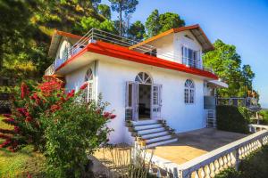 a small white house with stairs in a yard at StayVista at Misty Mountains Cottage in Kasauli