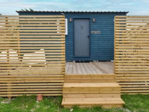 a blue house with a wooden deck with a door at Shepherds Beachhouse in Pagham