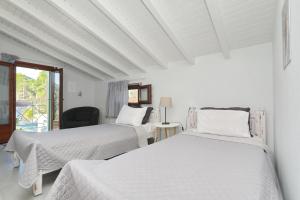 two beds in a white room with a window at Blue & Green Villa in Panormos Skopelos