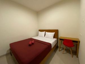 1 dormitorio pequeño con 1 cama y 1 silla roja en The Home Srengseng, en Yakarta