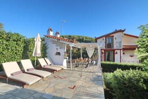 a patio with a group of chairs and an umbrella at Blue & Green Villa in Panormos Skopelos