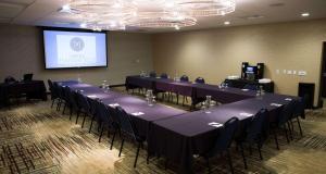a conference room with tables and chairs and a screen at Hotel Marshfield, BW Premier Collection in Marshfield