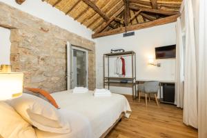 a bedroom with a white bed and a stone wall at Monte Forru in Baunei