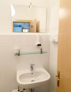 Baño blanco con lavabo y espejo en Rosengarten en Bolzano