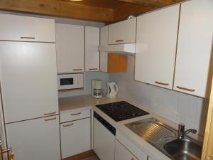 a small kitchen with white cabinets and a sink at Appartement Agostini in Sölden