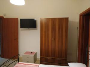 マティーノにあるVilla Fabianaのベッドルーム1室(木製キャビネット、壁掛けテレビ付)