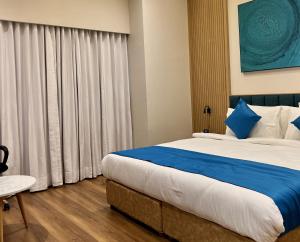 1 dormitorio con 1 cama grande con almohadas azules y blancas en Hotel Blueivy Anand, en Anand