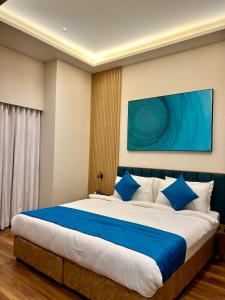 a bedroom with a large bed with blue pillows at Hotel Blueivy Anand in Anand