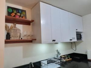 a kitchen with white cabinets and a sink at 1 BR Cozy Farmhouse-Style Condo with Balcony & Taal View at Wind Residences in Tagaytay